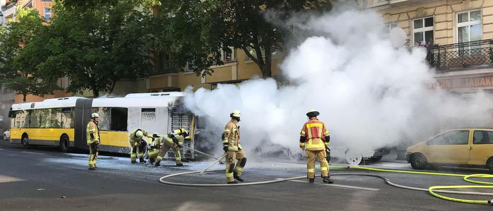 Feuerwehrleute löschen einen Brand an einem Bus der BVG in der Neuköllner Hermannstraße.