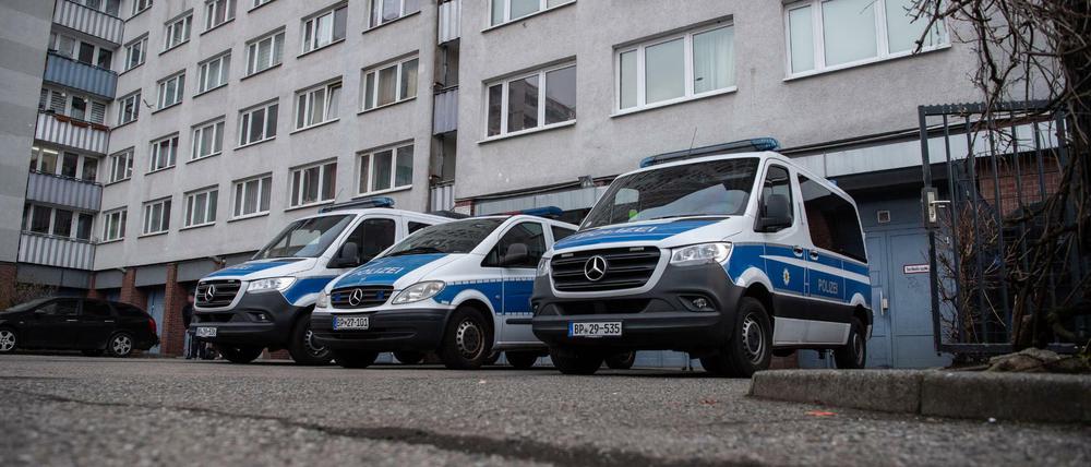 Einsatzfahrzeuge der Polizei bei der Razzia in Berlin-Lichtenberg vor einem Wohnhaus.