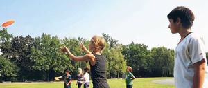 Mädchen und Jungen der Charlotte-Salomon-Schule spielen gemeinsam Frisbee im Sportunterricht.