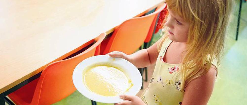 Mittagspause. An der Martin-Niemöller-Grundschule in Hohenschönhausen trägt ein Mädchen einen Teller mit Suppe zu einem Tisch. 