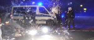 Polizeibeamte stehen hinter explodierendem Feuerwerk. Nach Angriffen auf Einsatzkräfte in der Silvesternacht hat die Diskussion um Konsequenzen begonnen.