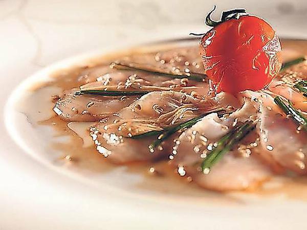 New Style Sashimi. Geschmacklich mit Sojasauce und Ingwer dem Nikkei-Stil verpflichtet, werden hier die rohen Fischfilets durch heiß angegossenes Sesamöl leicht angegart.