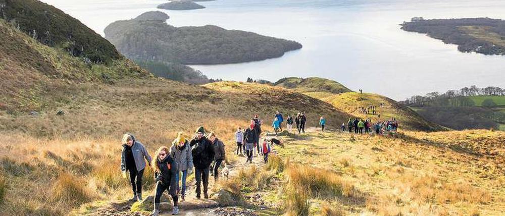 Familien wandern nahe dem Ort Balmaha den Conic Hill hinauf. Zur Belohnung gibt es einen Panoramablick auf Loch Lomond, Schottlands größten See.