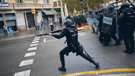 Ein spanischer Nationalpolizist zielt in Barcelona auf Menschen, die in einer Schule ihre Stimme abgeben wollen.
