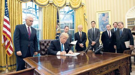 Die Mannschaft. Wenn Donald Trump Dekrete unterzeichnet, sind Vize-Präsident Mike Pence (links), Schwiegersohn Jared Kushner (4.v.r.), Strategieberater Stephen Bannon (ganz rechts) und Stabschef Reince Priebus (halbrechts hinter Trump) fast immer dabei.