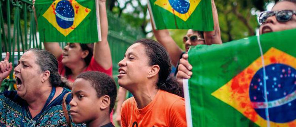 Bei der Beerdigung von Evaldo dos Santos Rosa zeigen Demonstranten eine brasilianische Flagge mit künstlichen Blutflecken. Soldaten hatten mehr als 80 Schüsse auf das Auto des Musikers abgegeben.