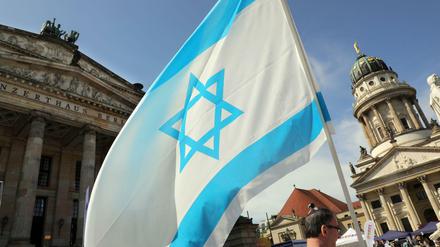 Mit einer israelischen Flagge gedenken Menschen 2018 auf dem Gendarmenmarkt der Unabhängigkeit Israels.