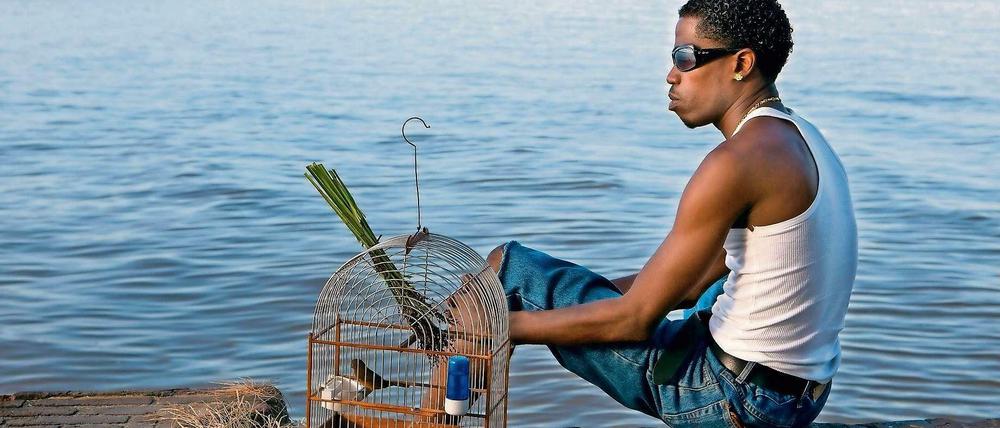 Ein Bewohner von Paramaribo mit seinem Vogel am Fluss Suriname.