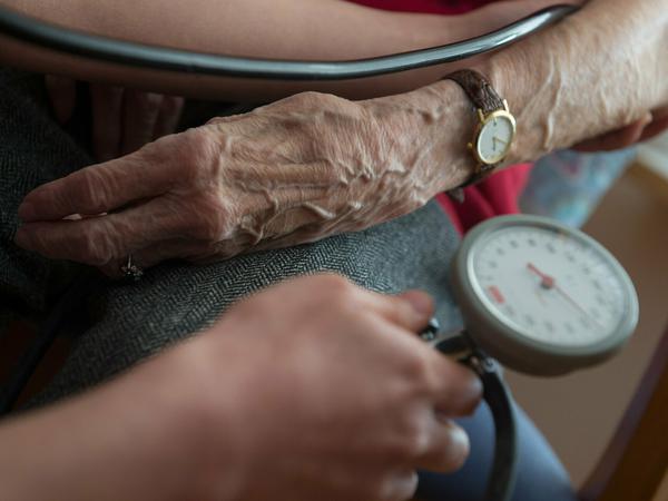 Eine Seniorin bekommt den Blutdruck gemessen.