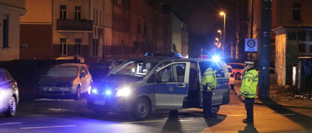 Polizisten stehen an einer durch ein Polizeifahrzeug blockierten Straße in Leipzig.