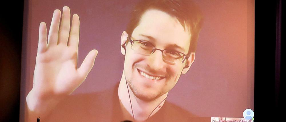 Der NSA-Enthüller Edward Snowden winkt während einer Videoschalte dem Publikum zu. Der US-Whistleblower Edward Snowden ist Vater geworden, das Foto ist aus dem Jahr 2014.