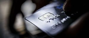 Eine Kreditkarte vom Typ VISA Card wird neben einer Computertatstatur gehalten. Oft kennen Bankkunden den Unterschied zu einer Debitkarte nicht. (Symbolbild)