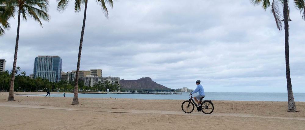 Ein Radfahrer fährt den leeren Waikiki Beach in Honolulu, Hawaii, entlang. 
