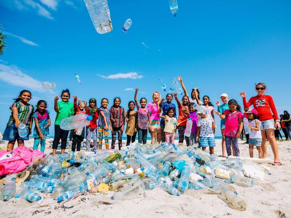 Mit einheimischen Kindern sammeln die Resortmitarbeiter Plastikmüll am Strand auf.