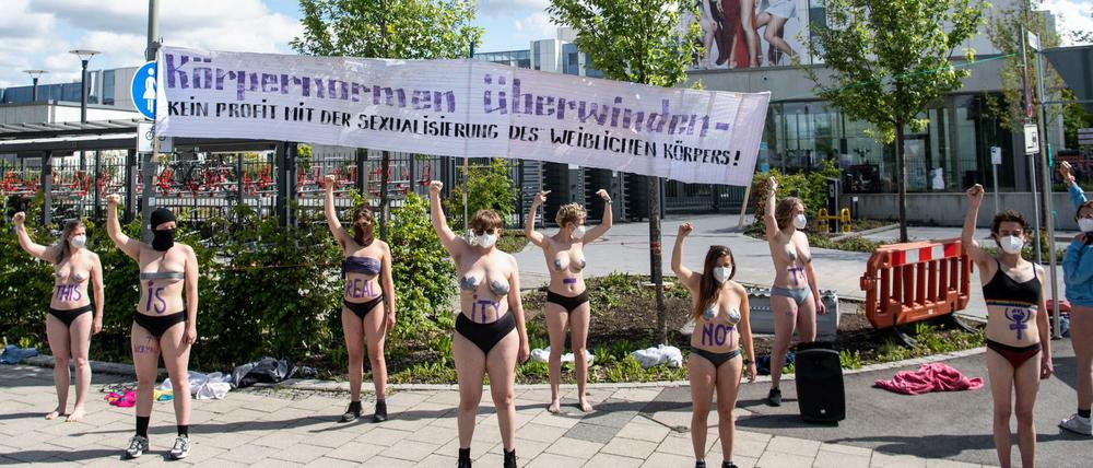 Mit Körperfarbe bemalte Aktivistinnen vom Augsburger Klimacamp demonstrieren vor einem Gebäude von ProSieben.
