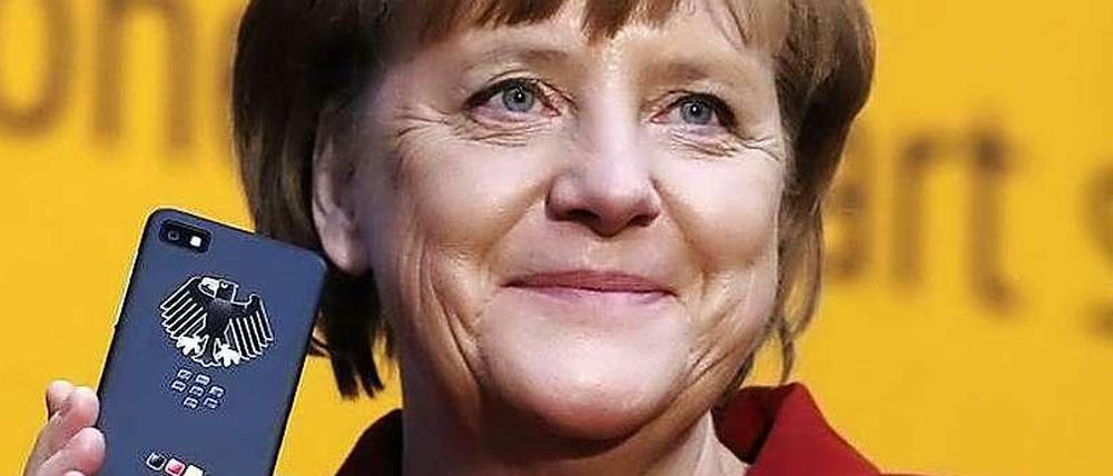 Bundeskanzlerin Angela Merkel hält ein Smartphone in der Hand.