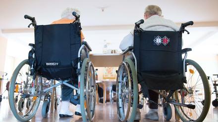 Zwei pflegebedürftige Frauen sitzen in einem Pflegeheim in ihren Rollstühlen nebeneinander.