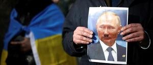 Demonstranten in London haben auf ein Putin-Foto ein Hitler-Bärtchen gemalt.