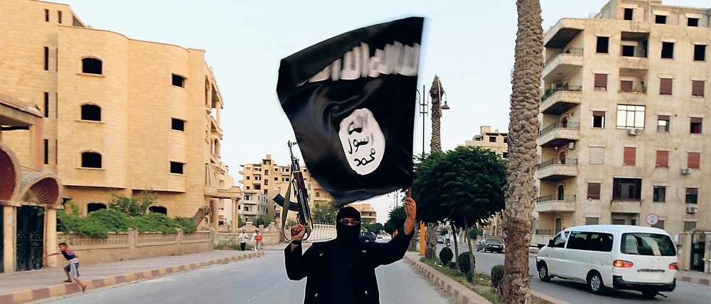 Ein Kämpfer trägt die Flagge des IS im Juni 2014 durch Raqqa. 