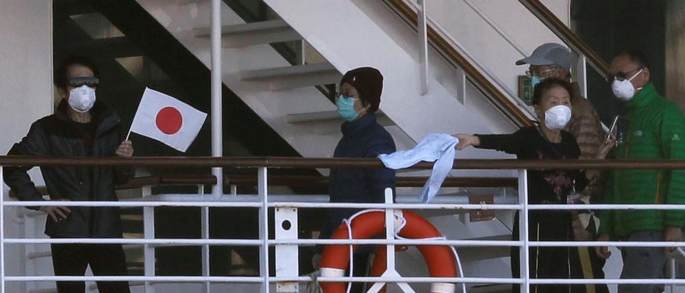 Coronavirus auf dem Kreuzfahrschiff: Passagiere auf der „Diamond Princess“ winken mit Flaggen und Tüchern.