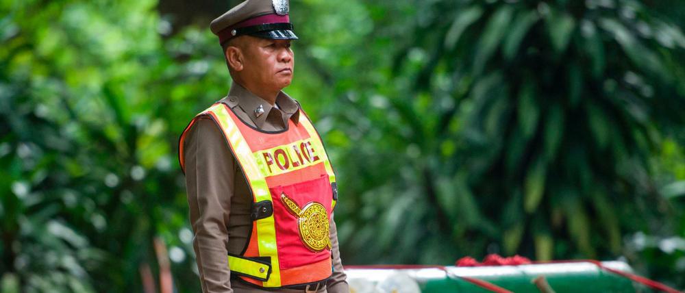 Ein Polizist vor Sauerstofftanks zur Rettung der Eingeschlossenen in der thailändischen Höhle 