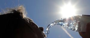 Bei Temperaturen um 33 Grad Celsius erfrischt sich eine junge Frau in Berlin-Spandau mit sprudelndem Mineralwasser. 
