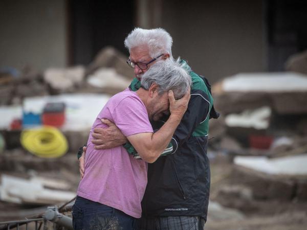 Weinend liegen sich zwei Brüder wenige Tage nach der Flutkatastrophe vor ihrem von der Flut zerstörten Elternhaus in Altenahr-Altenstadt in den Armen.