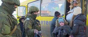 Soldaten beobachten, wie Evakuierte aus der ukrainischen Region Charkiw an der russischen Grenze aus einem Bus aussteigen (Archivbild).