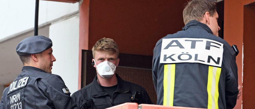 Polizisten und ein Feuerwehrmann stehen im Juni auf dem Balkon einer Wohnung in Köln-Chorweiler.