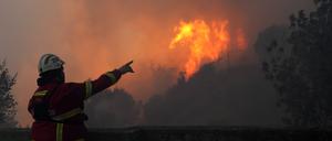 Ein Feuerwehrmann zeigt auf den Waldbrand, der in Alcabideche, außerhalb von Lissabon, wütet (Symbolbild).