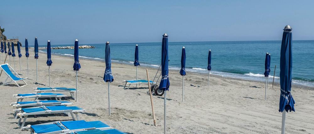 Strandliegen und Sonnenschirme stehen in Ligurien am Strand von Ligurien. 