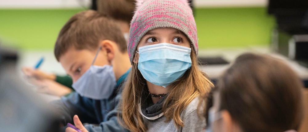 Mit Mundschutzmasken sitzen Schülerinnen und Schüler der fünften Klasse eines Gymnasiums in Frankfurt am Main im Unterricht. 