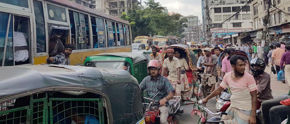 Autos, Busse, Mopeds, Motorräder, Fahrräder, Rikschas und Handkarren teilen sich in Dhaka die Straße.