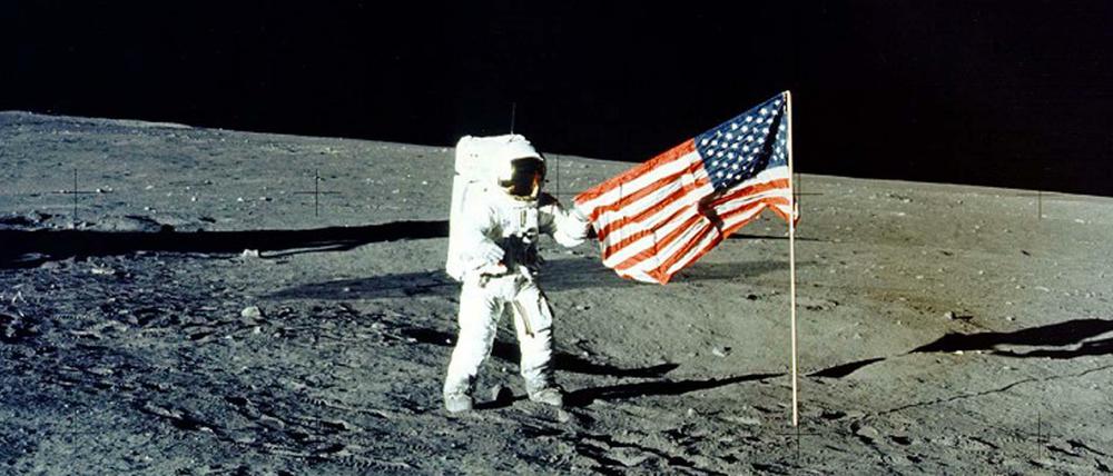 Im „Meer der Stürme“. Astronaut Charles „Pete“ Conrad posiert vor der US-Flagge. Apollo 12 war die zweite bemannte Mondlandung im Apollo-Programm.