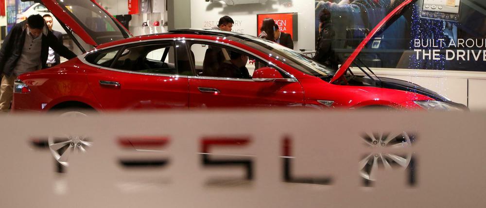 Ein Mann schaut in einem Showroom in Peking in einen Tesla Model S. 