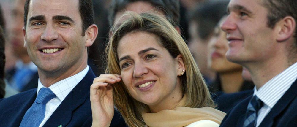 König Felipe von Spanien (l) sitzt im Jahre 2003 neben seiner Schwester Cristina und deren Mann Inaki Urdangarin. Aufgrund einer Finanzaffäre wurde Cristina der Fürstentitel aberkannt. 