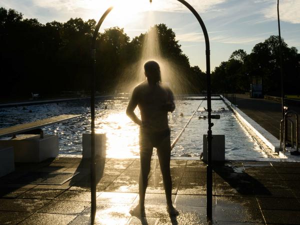 Ein Mann duscht am frühen Morgen im Freibad Annabad, Hannover, im Licht der aufgehenden Sonne. (Archivbild)