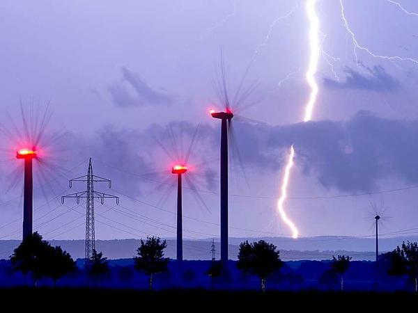 Blitze zucken am späten Dienstagabend über Windräder bei Algermissen im Landkreis Hildesheim in Niedersachsen. Noch ist die Unwetter-Gefahr nicht gebannt. 