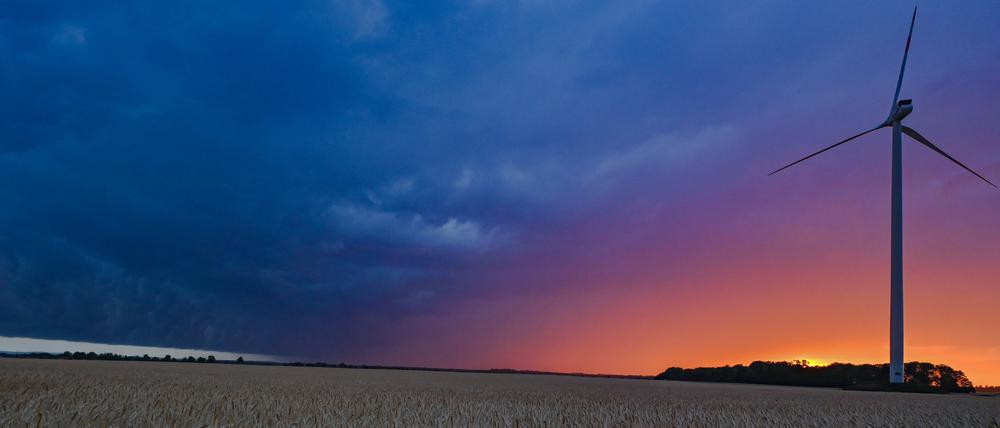 In Brandenburg leuchtet der Sonnenuntergang hinter einer Gewitterzelle mit dunklen Regenwolken.