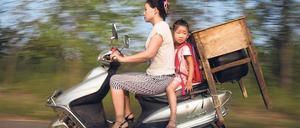 Erster Schultag. Die kleine Lu Siling fährt in der Stadt Shunhe eingezwängt zwischen Mutter und Pult zur Schule. 
