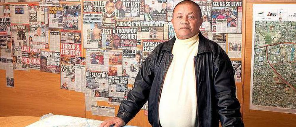 Ex-Gangster Nealon Petersen in seinem Büro vor einer Wand voller Schlagzeilen, die von der gewalttätigen Realität in den armen Vororten Kapstadts erzählen. 