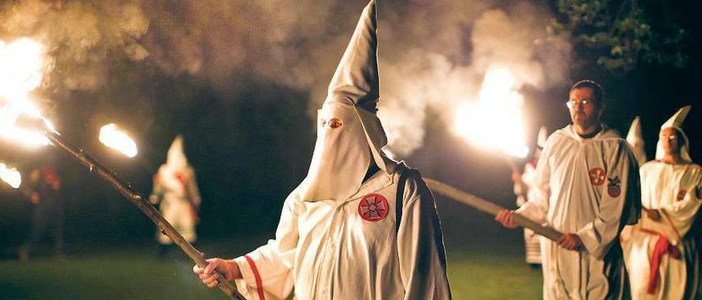 Zeremonie mit weißen Kutten und Spitzhauben. Die Bekleidung hatte der Ku-Klux-Klan Ende des 19. Jahrhunderts gewählt, um abergläubische Schwarze zu erschrecken.