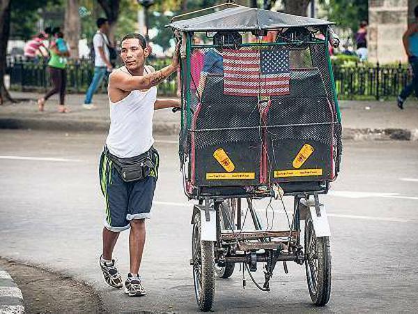 Unter US-Flagge radelt dieser Fahrrad-Taxifahrer durch Havanna.