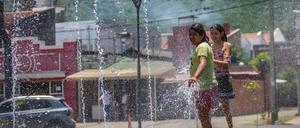 Mädchen erfrischen sich an einem Brunnen in Salta während einer heftigen Hitzewelle in Argentinien. 