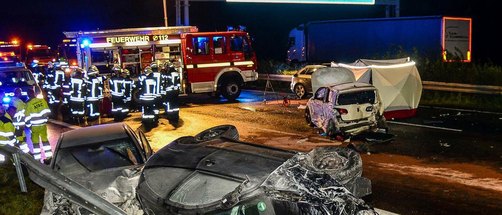 Feuerwehrleute stehen am 12.09.2017 auf der Autobahn 2 bei Oelde (Nordrhein-Westfalen) neben zerstörten PKW. 