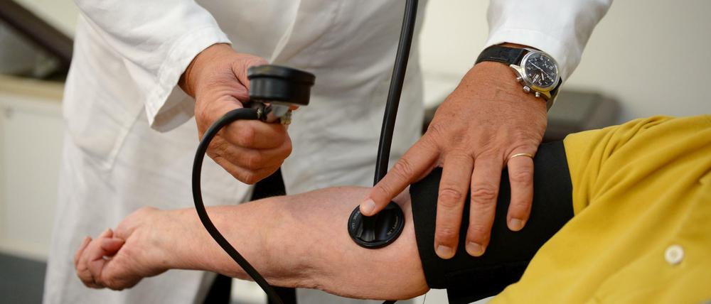 Ein Hausarzt misst einer Patientin den Blutdruck. 