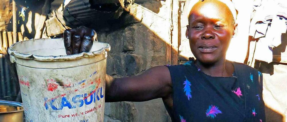 Eine Frau in Kenia bereitet eine Wanne mit Bier zum Baden gegen Masern vor. 
