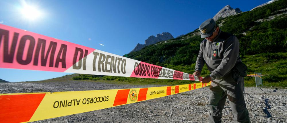 Ein Beamter der italienischen Finanzpolizei blockiert den Zugang zum Marmolada-Berg und zum Punta-Rocca-Gletscher in den italienischen Alpen mit Absperrband. 