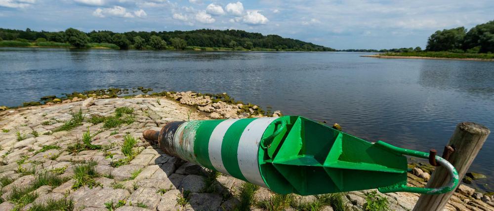 Eine sogenannte Tonne für die Schifffahrt liegt auf einer Steinbuhne am Ufer der Elbe. 