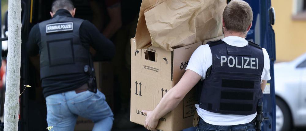 Polizisten tragen Gegenstände aus dem Wohnhaus des Tatverdächtigen.